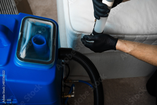 Cleaner is using extractor machine to clean the bed mattress in the house. Absorbing the dirt from the fibers of sofa with extractor. Mattress dry washing using extractor.