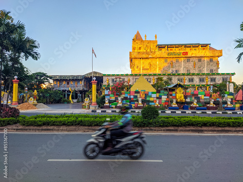 Obraz na płótnie Unique castle-like hotel in Batam city, adorned with colorful decorations and a small pyramid at its base, standing prominently on a street corner under a clear blue sky w salonie