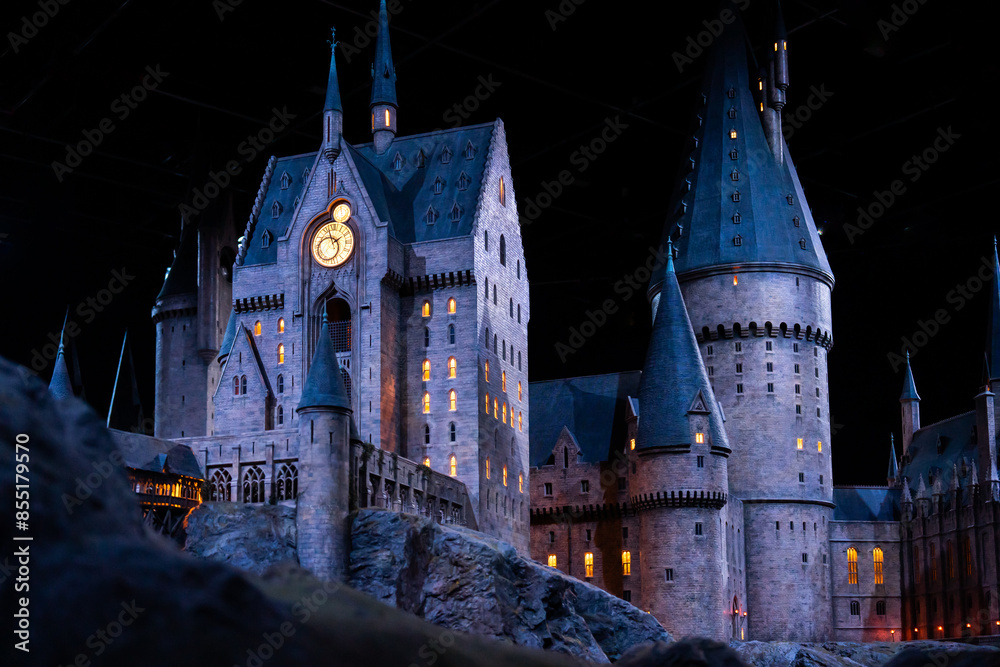 Obraz premium JAPAN - Nov 13, 2023: Closeup night view of Hogwarts Castle's clock tower illuminated beautifully highlighting its magical architecture at Warner Bros. Studio Tour Tokyo, The Making of Harry Potter