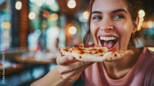 Joyful woman taking a bite of pizza in a vibrant, cozy restaurant setting, enjoying her meal.
