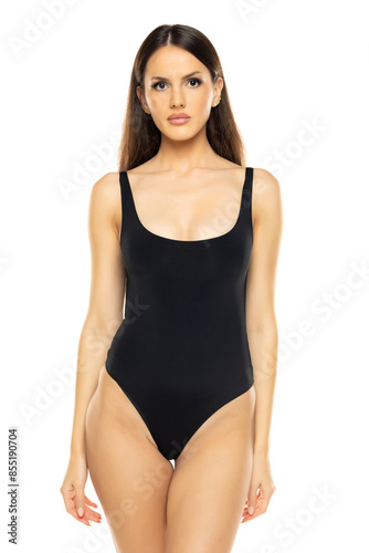 Young brunette woman in one piece bikini swimsuit posing on a whitestudio background. Front view.