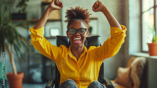 Happy disabled woman in a wheelchair winning. African american colleague with disability celebrating job success photo