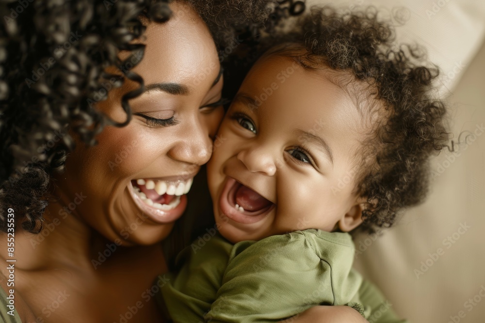 A beautiful African American mother cuddles her baby girl laughing and playing with his daughter A beautiful African American mother cuddles her baby girl laughing and playing with his daughter
