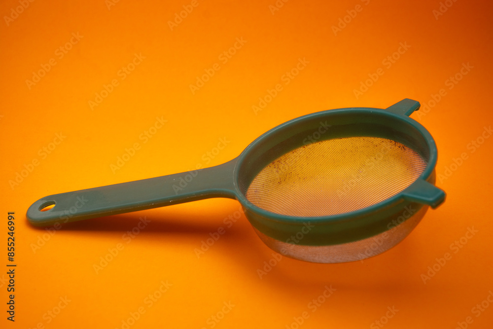 close up of a used green tea strainer on an orange background close up of a used green tea strainer on an orange background