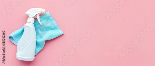 White spray bottle with blue microfiber cloth on pink background