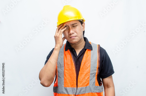 Asian male construction worker in fatigue looks tired and have headaches after hard working. man in yellow safety hardhat and orange vest have overworked.