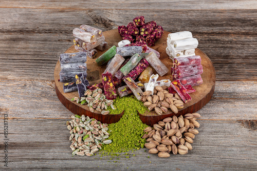 Assortment of Turkish delight with pistachio wick on a wooden background. Traditional Turkish cuisine delicacies. Mixed Wick Turkish Delight with Pistachio local name; Fistikli  karisik fitil lokum. photo