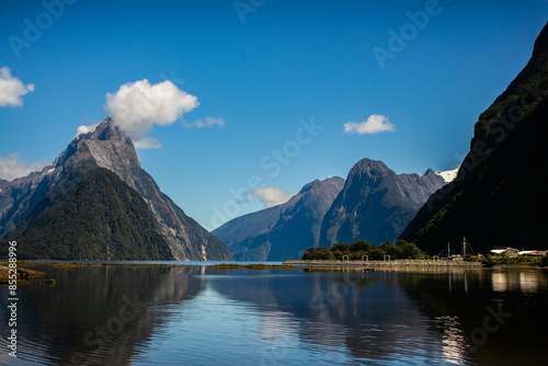 A stunning fjord with towering mountains reflected in calm waters, under a clear blue sky, capturing the majestic beauty of nature.