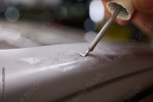 A man repaints a scratch on a car part in an auto repair shop with precision and craftsmanship photo