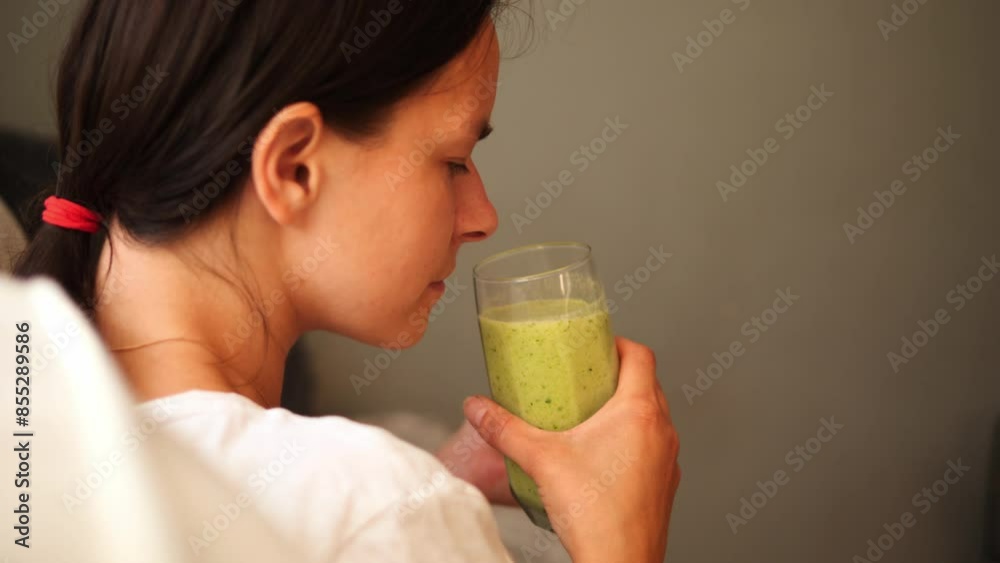 Young brunette woman sniffing glass with green smoothie in one hand and green apple in other. Perfect for health and wellness content fresh smoothie ingredients and benefits for nutritious lifestyle. Young brunette woman sniffing glass with green smoothie in one hand and green apple in other. Perfect for health and wellness content fresh smoothie ingredients and benefits for nutritious lifestyle.