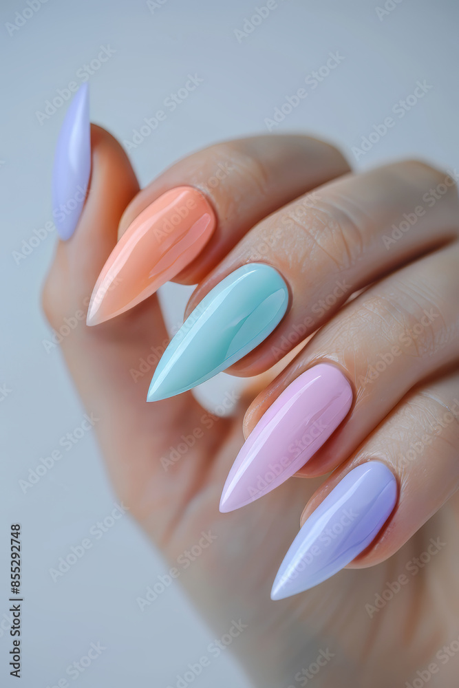 Close-up of a hand flaunting glossy, multicolored stiletto nails in pastel colors against a neutral background Close-up of a hand flaunting glossy, multicolored stiletto nails in pastel colors against a neutral background