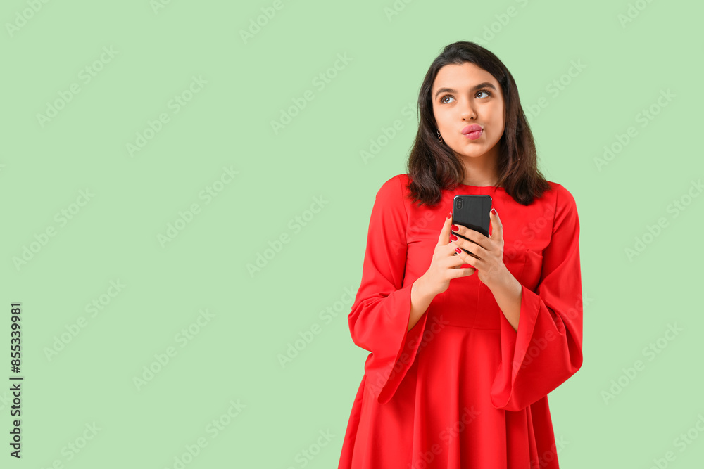 Thoughtful young woman with mobile phone on green background. Online dating concept Thoughtful young woman with mobile phone on green background. Online dating concept