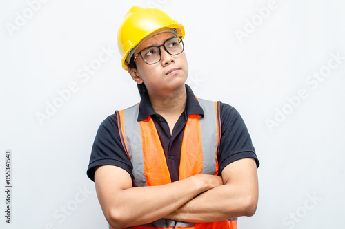 Title	
young asian man construction worker using yellow helmet and orange vest makes a thinking gesture. asian male worker in pensive expression while thinking looking for idea.