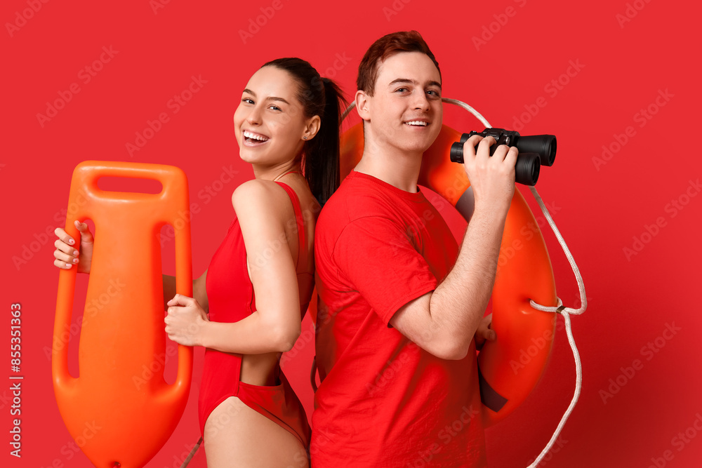 Lifeguards with ring buoy, rescue tube and binoculars on red background Lifeguards with ring buoy, rescue tube and binoculars on red background