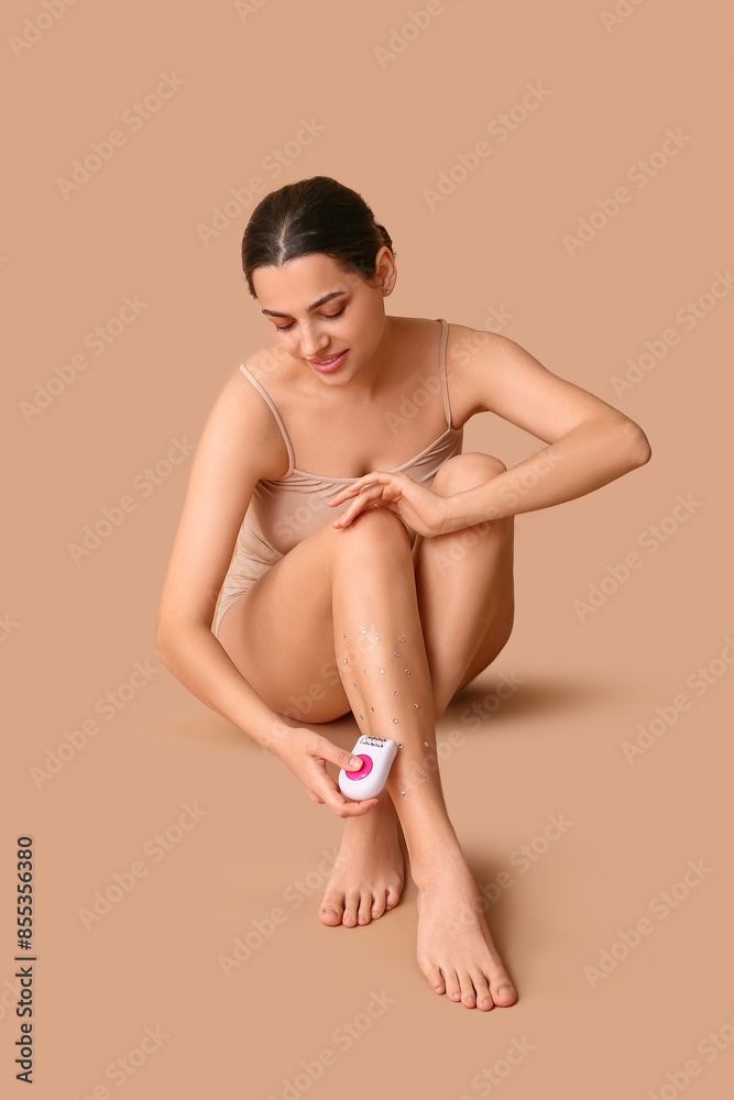 Beautiful young happy woman with modern epilator and precious stones on beige background. Depilation concept Beautiful young happy woman with modern epilator and precious stones on beige background. Depilation concept