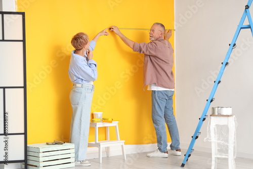 Mature couple measuring wall during repair in their new house