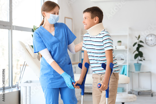 Injured little boy with crutches and doctor in clinic