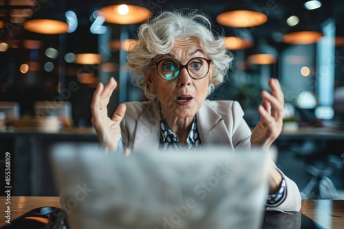 Senior businesswoman shows intense reaction to laptop content in a modern office