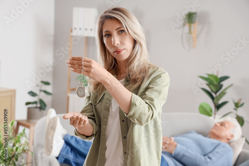 Female hypnotist with pocket watch in office