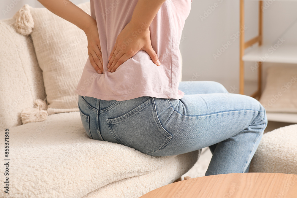 Young woman suffering from back pain on sofa at home, closeup Young woman suffering from back pain on sofa at home, closeup