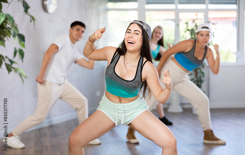 Fototapeta premium Group of young women and young guy perform hip hop dance moves in dance hall