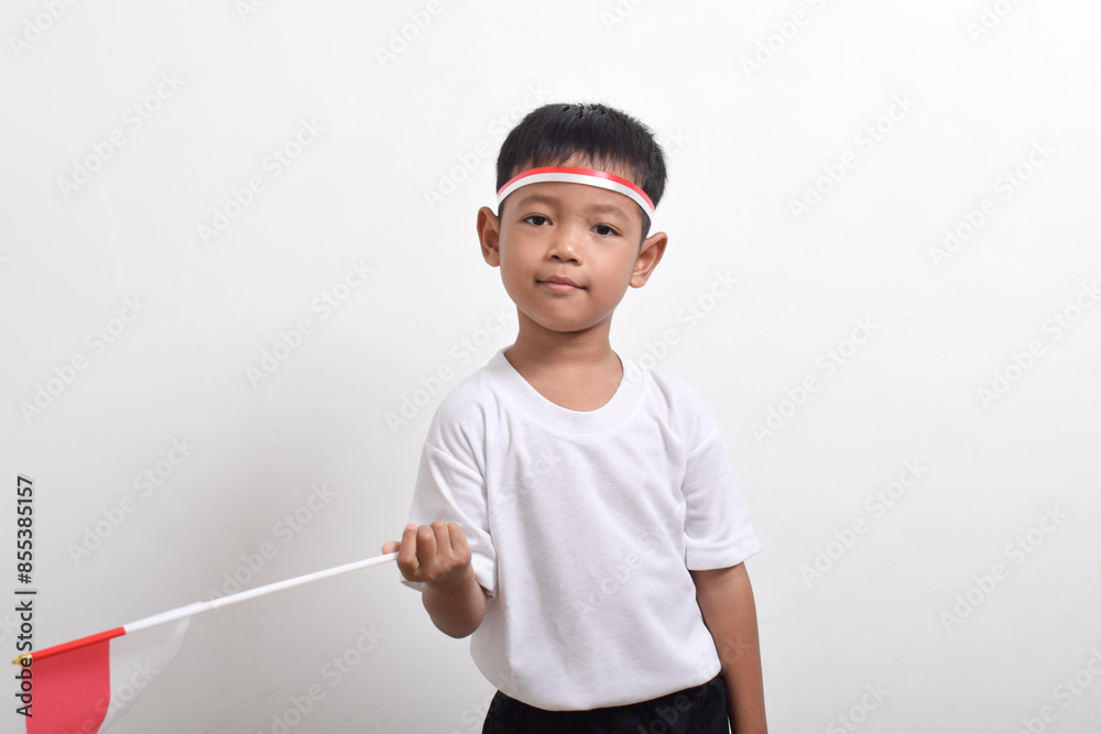 Cute little Asian boy holding Indonesia's flag to celebrate Indonesia Independence Day isolated on white background.