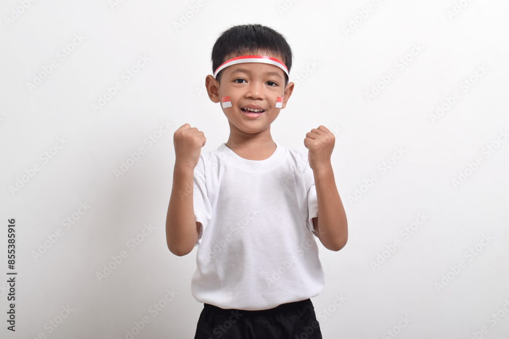 Cute little Asian boy with successful happy expression wearing white t-shirt holding Indonesian flag to celebrate Indonesian Independence Day on August 17 isolated on white background. Cute little Asian boy with successful happy expression wearing white t-shirt holding Indonesian flag to celebrate Indonesian Independence Day on August 17 isolated on white background.