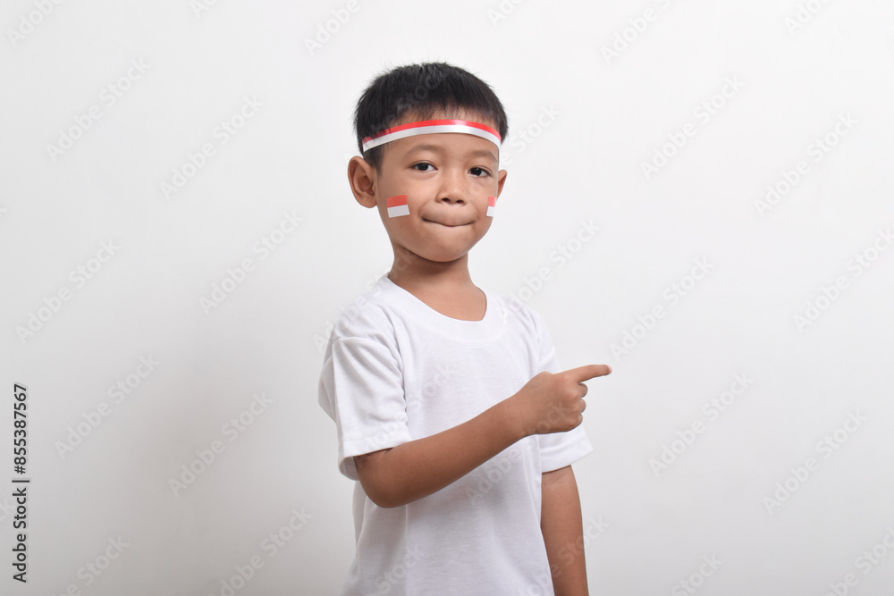 Cute little Asian boy wearing flag headband pointing at the copy space beside himi solated on white background. Concept of Indonesia's independence day on August 17 Cute little Asian boy wearing flag headband pointing at the copy space beside himi solated on white background. Concept of Indonesia's independence day on August 17