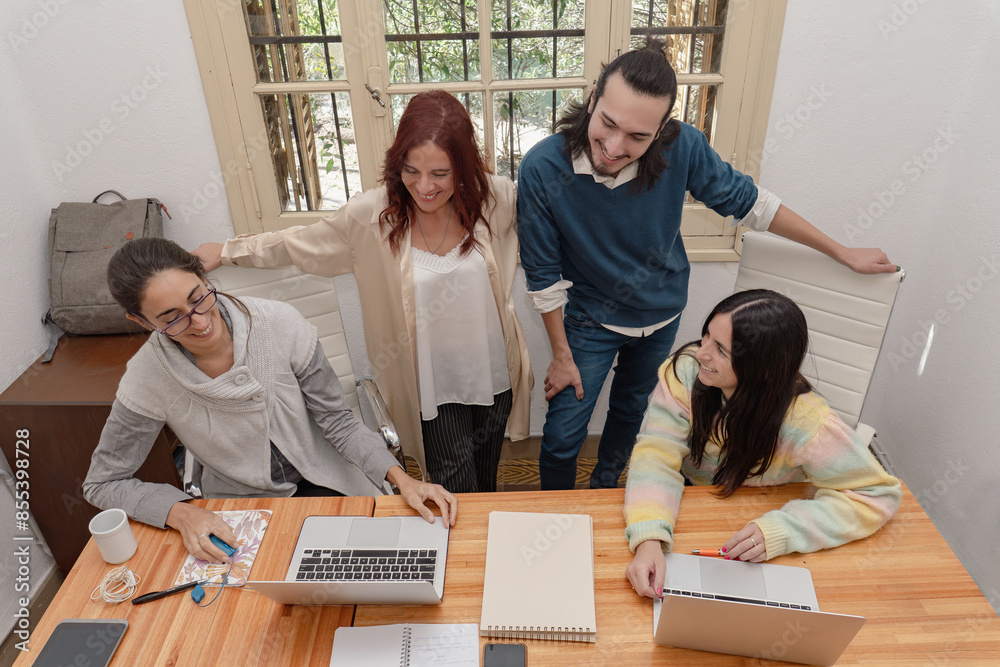 Business colleagues reviewing report with laptop in modern office.