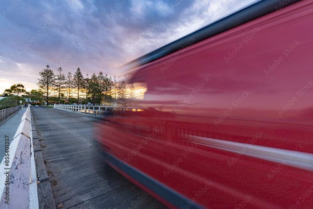 Red van with motion blur crossing bridge at sunset