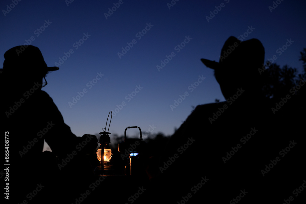 Obraz premium 夕暮れのキャンプを楽しむシルエットの男性二人