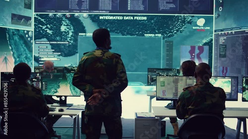 Army officer examining satellite surveillance footage on a big screen for reconnaissance, gathering intelligence to ensure national safety. Secret service federal agency works on defense. Camera B.
