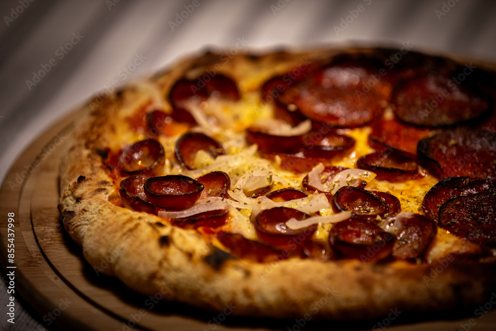 Calabrian sausage pizza served on a round board and set table Calabrian sausage pizza served on a round board and set table