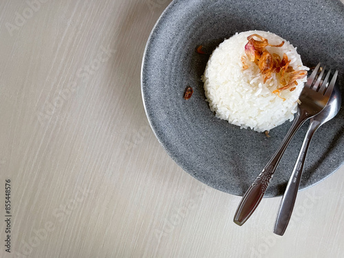 White rice sprinkled with fried shallots with a fork on the table. Copy space. photo