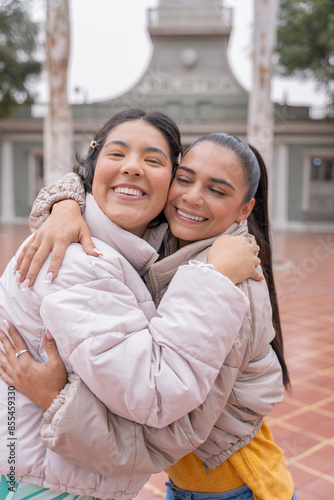 Close-up of women embracing in the street smiling at camera