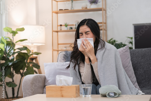 Sick Woman Sneezing on Sofa with Tissue Box and Blanket in Cozy Living Room Setting