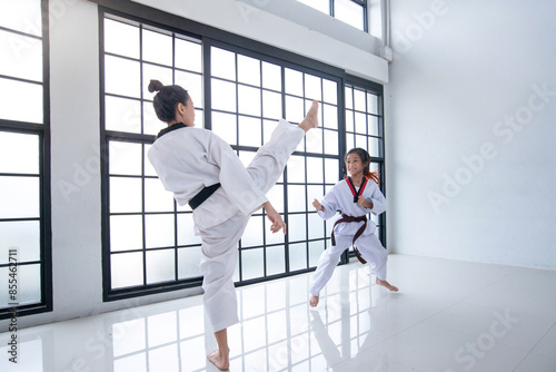 Little girl and her Taekwondo coach are practicing kicks to use in a competition, fighting training in the gym, Taekwondo training concept