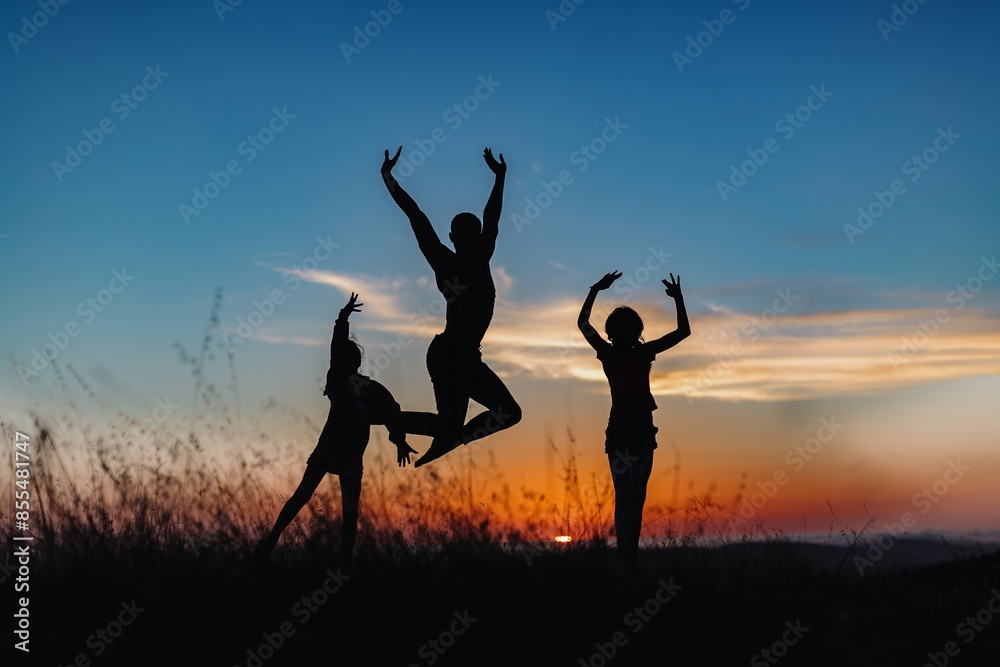 Silhouette of male ballet dancer and two children jumping and doing a majestic jump for joy in nature, Behind them are heavenly clouds and the sun is setting. Silhouette of male ballet dancer and two children jumping and doing a majestic jump for joy in nature, Behind them are heavenly clouds and the sun is setting.