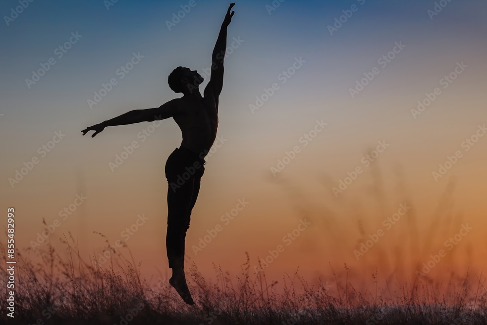 Silhouette of male ballet dancer jumping and doing a majestic dance move in nature, Behind him are heavenly clouds and the sun is setting.
