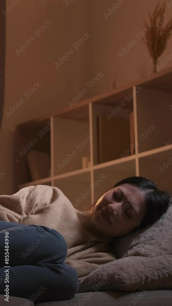 Vertical video. Period pain. Pms cramps. Sick unwell woman suffering from stomach ache lying couch in dark home room interior. Vertical video. Period pain. Pms cramps. Sick unwell woman suffering from stomach ache lying couch in dark home room interior.