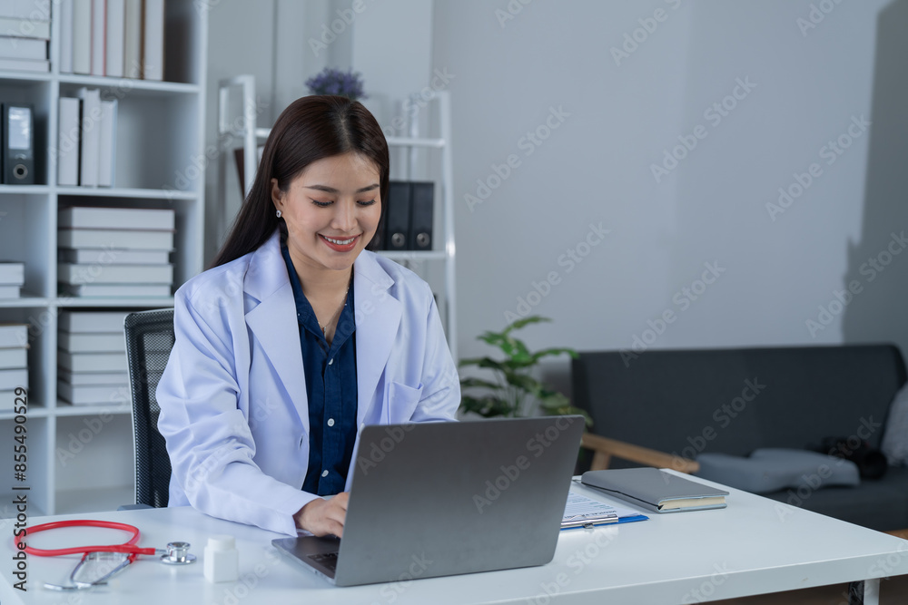 A photograph of a female doctor sitting at her desk in an office.