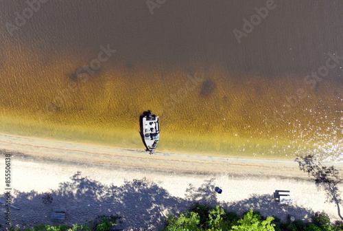 Small boat moored on a white sand beach on the Ottawa River on a sunny day