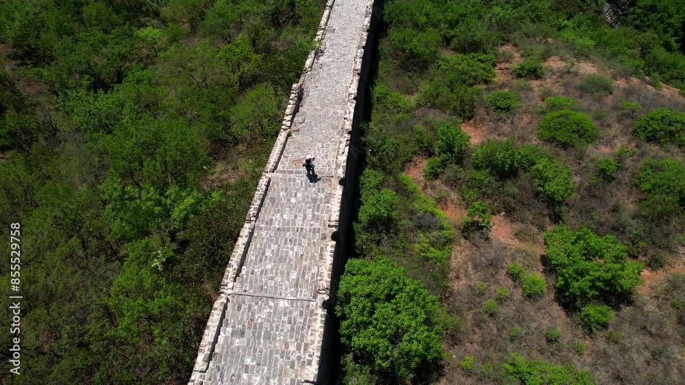 Aerial top down view of solitaire woman standing on top of the Great Wall of China at noon in Jinshanling Section. Aerial top down view of solitaire woman standing on top of the Great Wall of China at noon in Jinshanling Section.