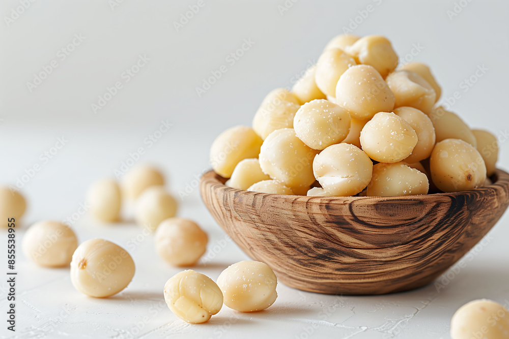 Close-up of Macadamias. The Macadamias in a wooden bowl are detailed and demonstrate their unique shape and texture on a plain white background. Close-up of Macadamias. The Macadamias in a wooden bowl are detailed and demonstrate their unique shape and texture on a plain white background.