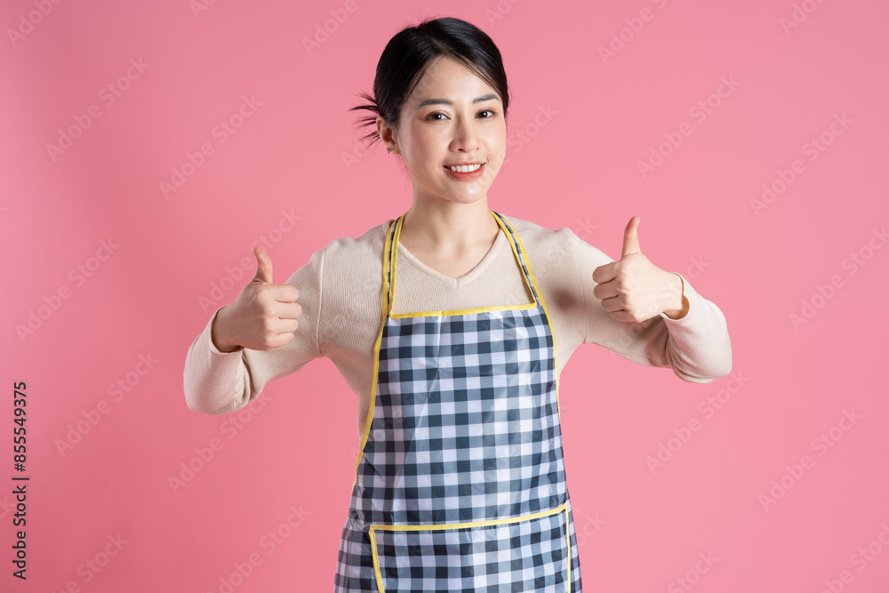 Portrait of woman wearing apron, posing on pink background Portrait of woman wearing apron, posing on pink background
