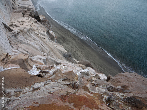 Looking down to Ibusuki rocky coast black sand beach with steam rising from hot ground from the top of the cliff