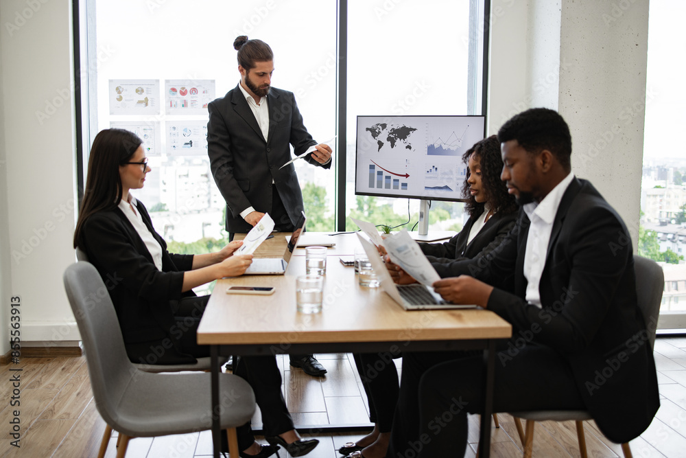 Group reviewing charts and graphs during presentation led by colleague. Team of professionals in business meeting discussing financial reports and data analysis. Group reviewing charts and graphs during presentation led by colleague. Team of professionals in business meeting discussing financial reports and data analysis.