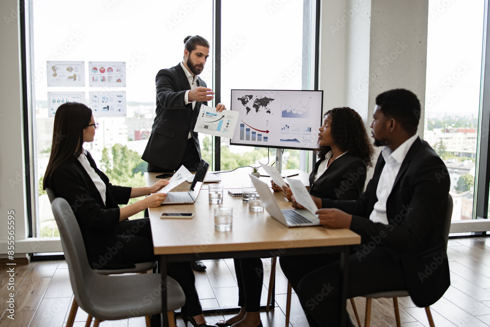 Business team engaged in discussion about financial report in meeting room. Professional setting with diverse coworkers analyzing charts and graphs on screen. Business team engaged in discussion about financial report in meeting room. Professional setting with diverse coworkers analyzing charts and graphs on screen.