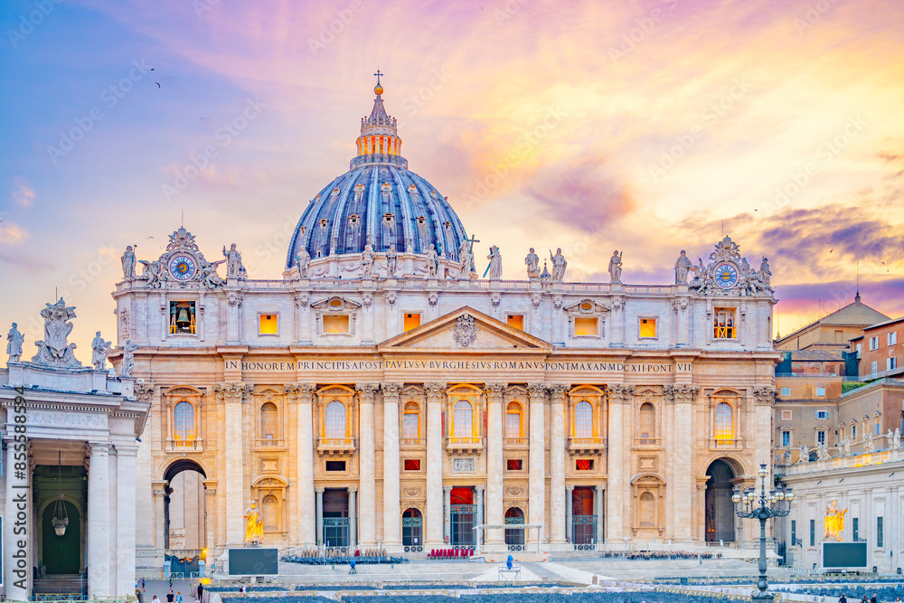 Obraz premium This image shows the front facade of St. Peters Basilica in Vatican City, Italy at sunset. The Basilica is bathed in warm golden light, highlighting its intricate