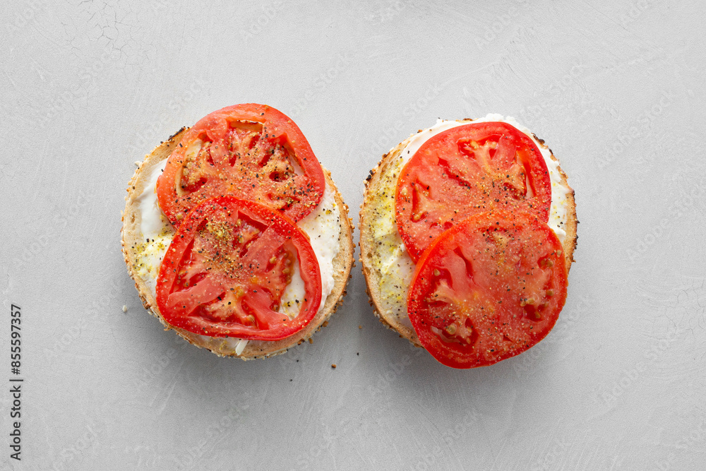 A top down view of a bagel with tomato, cream cheese and lemon pepper. A top down view of a bagel with tomato, cream cheese and lemon pepper.